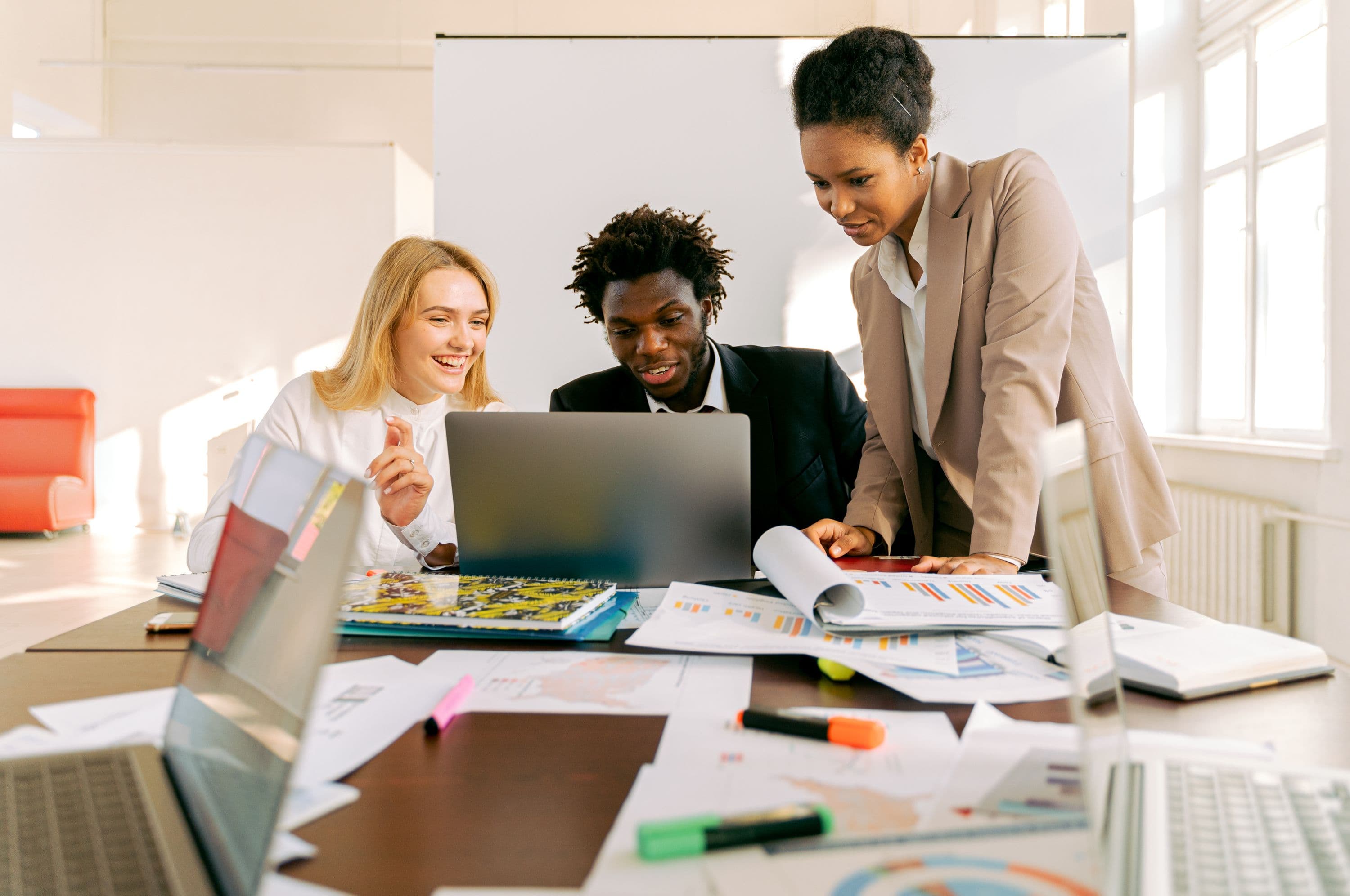 Three young professionals reviewing market data around a laptop